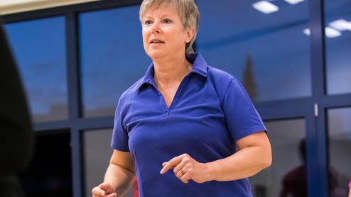 Eine Frau in blauer Sportkleidung springt auf einem Trampolin in einem Fitnessraum.