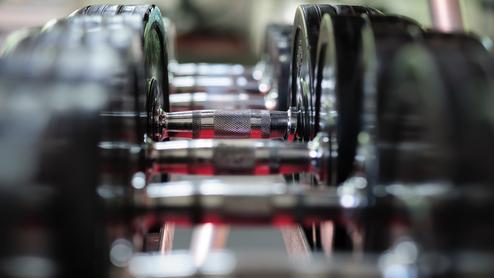 Nahaufnahme von Gewichten auf einer Hantelbank mit glänzenden Griffstangen zwischen den schweren und schwarzen Gewichten.