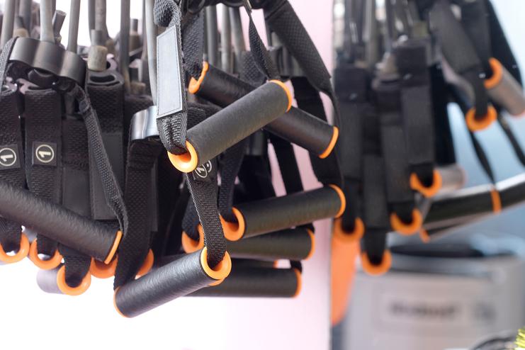 Nahaufnahme von mehreren schwarz-orangen Fitnessgriffen, die an einem Gestell befestigt sind.
