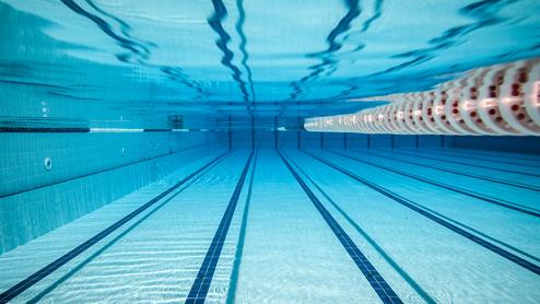 Unterwasseransicht eines Schwimmbeckens mit klaren, blauen Wasser und markierten Bahnen.
